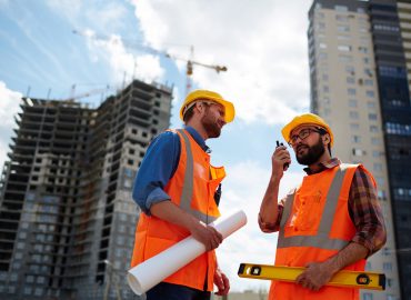 Contractor speaking on walkie-talkie with co-worker near by